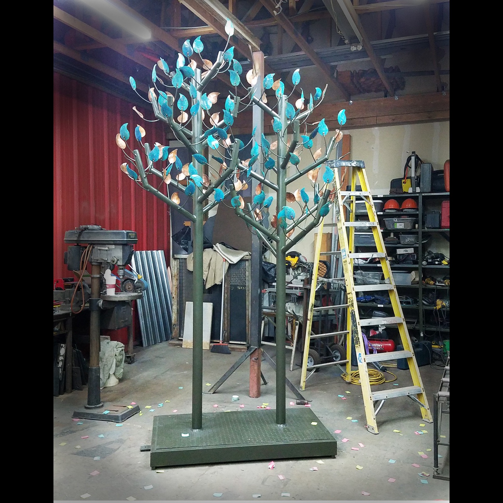 Two steel trees growing side by side, their branches full of turquoise and copper-colored leaves.